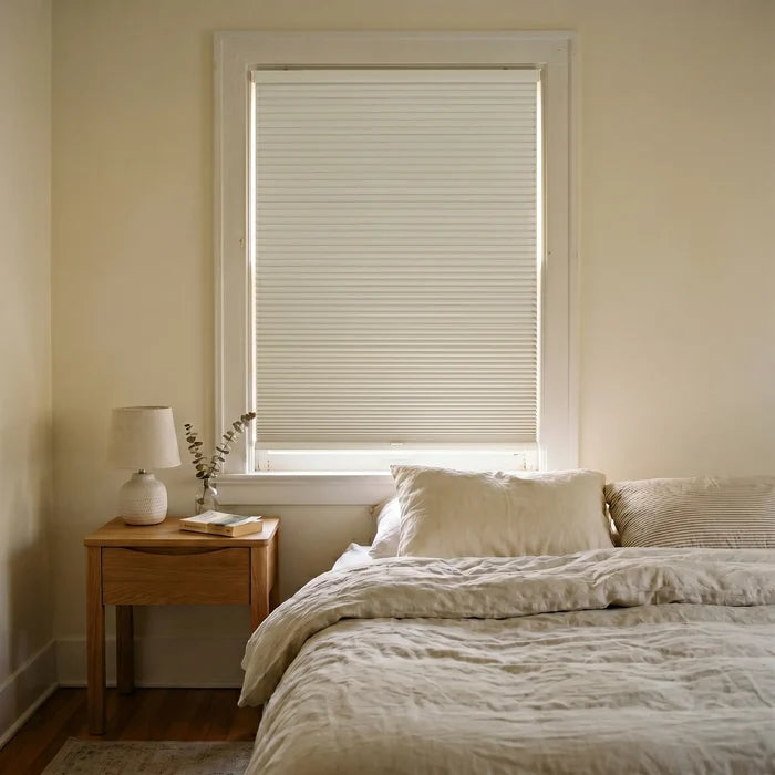Sunlight hits the Creamy White (White Dove) 9 16 Inch Classic Single Cell Blackout Cordless Shades in this modern bedroom, creating a serene, light-free setting.
