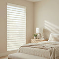 Light diffusing sheer shades elegantly scattering light in a clean natural toned bedroom.