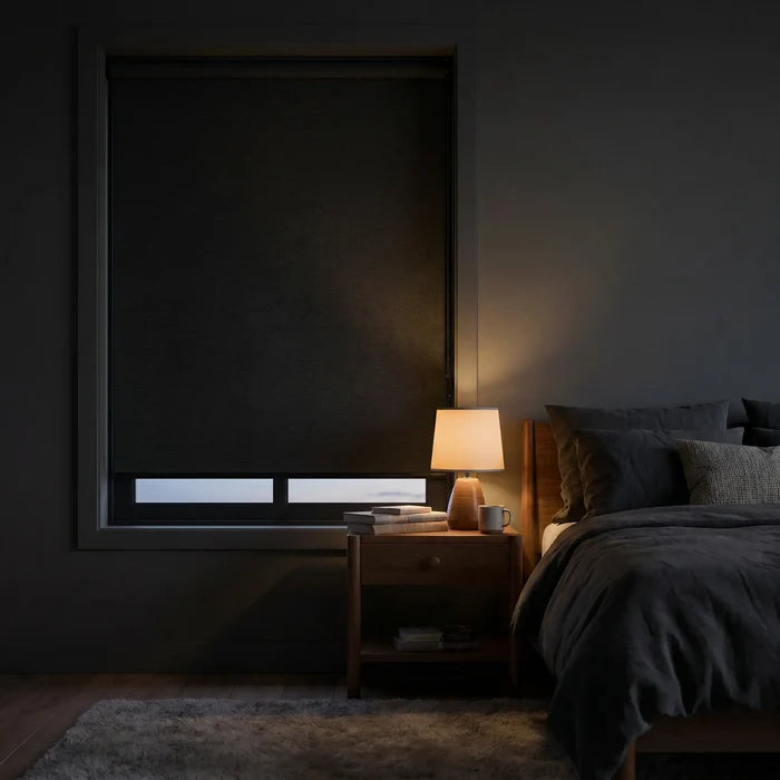 Marine Black Luxe fabric blackout roller shades in a dim bedroom setting with a warm bedside lamp, showcasing the high-quality light-blocking fabric