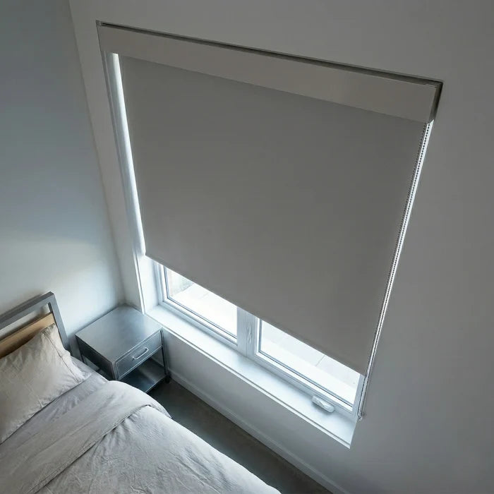 Gray ProGrade blackout roller shade seen from a bedside perspective, ideal for sleep optimization and privacy.