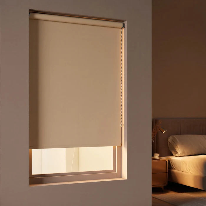 Elegant beige Sand signature blackout roller shades providing total light blockage in a contemporary bedroom.