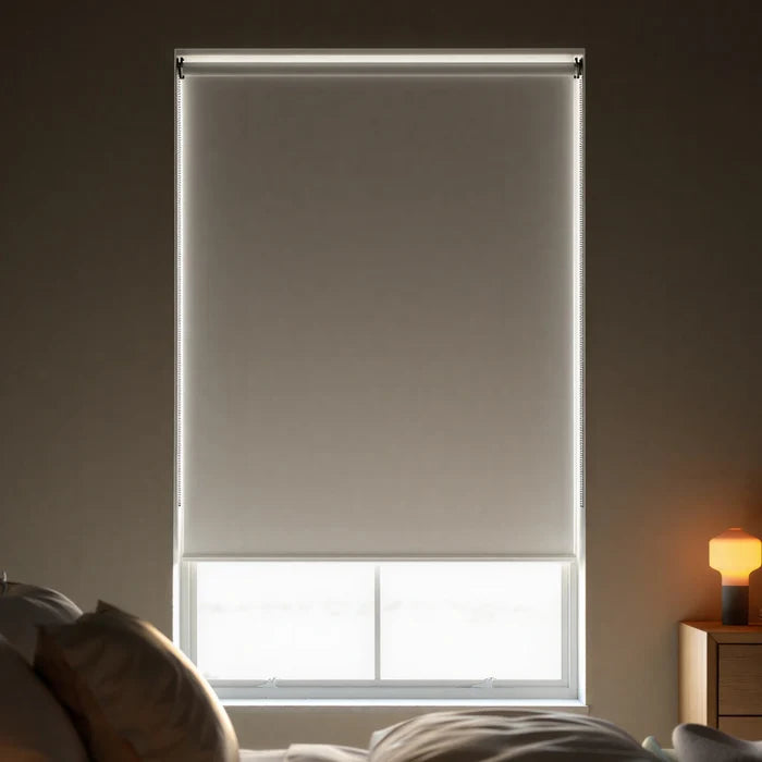Close-up view of light grey creme signature room darkening roller shades, showing the fabric texture and clean window fit.