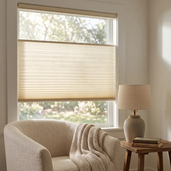 Simplistic Cordless Tdbu Pleated Shades effortlessly filter bright sunlight through beige treatments, complementing white walls and furniture in this serene room where versatility meets relaxation.